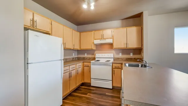 Bright and spacious kitchen with modern white appliances, abundant wooden cabinetry, and sleek countertops, ideal for cooking enthusiasts.