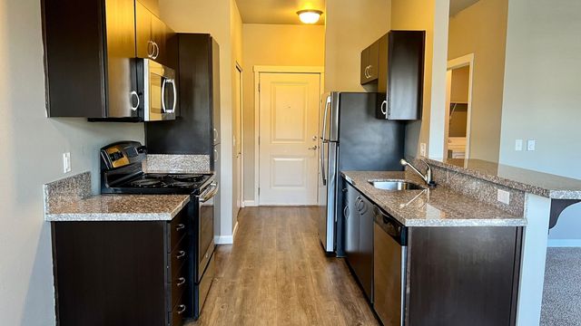 Contemporary kitchen with sleek dark cabinets, stainless steel appliances, and granite countertops.