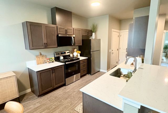 Modern kitchen with sleek dark wood cabinets, stainless steel appliances, and elegant white countertops, perfect for home chefs.