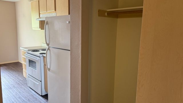 Inviting kitchen space with modern appliances, featuring a sleek white refrigerator and oven, complemented by wooden cabinets and durable flooring.