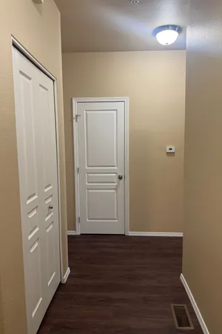 Inviting hallway in modern apartment featuring elegant hardwood floors and stylish white doors, creating a warm and welcoming entrance.
