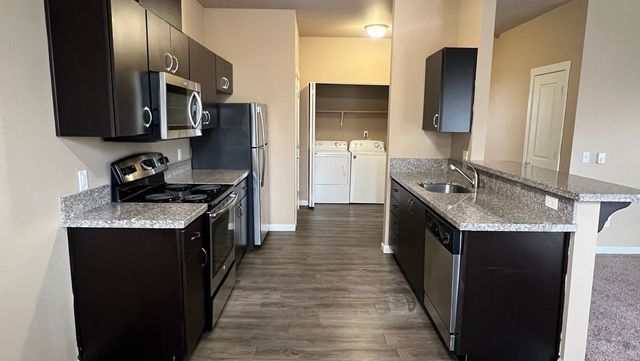 Modern kitchen with sleek cabinetry, stainless steel appliances, and granite countertops leading to a convenient laundry area.