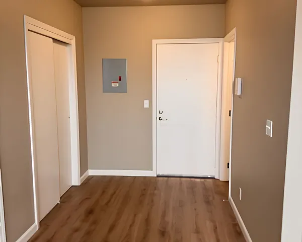 Inviting apartment entrance with sleek wood flooring, modern white doors, and a neutral color palette for a fresh, contemporary look.