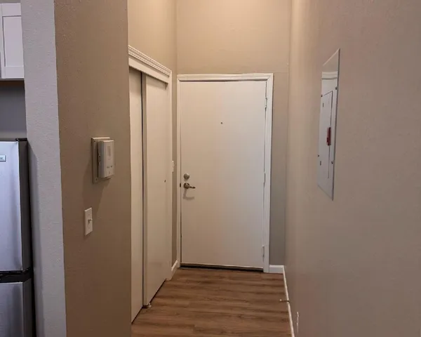 Welcoming apartment entryway with sleek hardwood flooring, neutral wall tones, and modern accents.