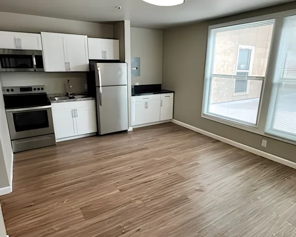 Modern kitchen with sleek stainless steel appliances, elegant white cabinetry, spacious open layout, and large sunlit windows.