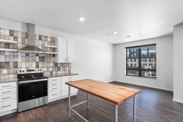 Modern kitchen featuring sleek stainless steel appliances, stylish backsplash, and a spacious wooden island in a bright open layout.