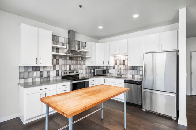 Modern kitchen with sleek stainless steel appliances, white cabinetry, and a stylish wooden island.