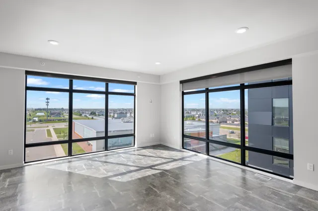 Bright, spacious room with floor-to-ceiling windows offering a panoramic city view; perfect for modern living.