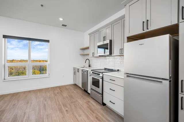 Bright and modern kitchen with sleek appliances, ample cabinetry, and a scenic window view.