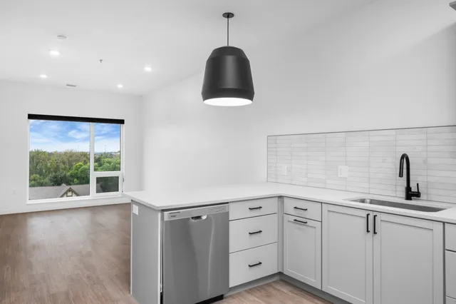 Modern kitchen with sleek stainless steel appliances, spacious white countertops, and a large window with scenic views.