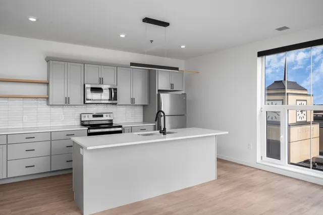 Bright, modern kitchen with sleek cabinetry, stainless steel appliances, and large window offering stunning views.