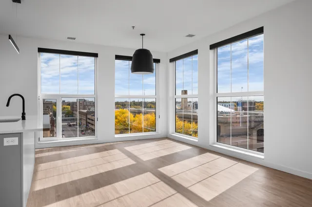 Bright, open apartment space with large modern windows offering a stunning city view and abundant natural light.