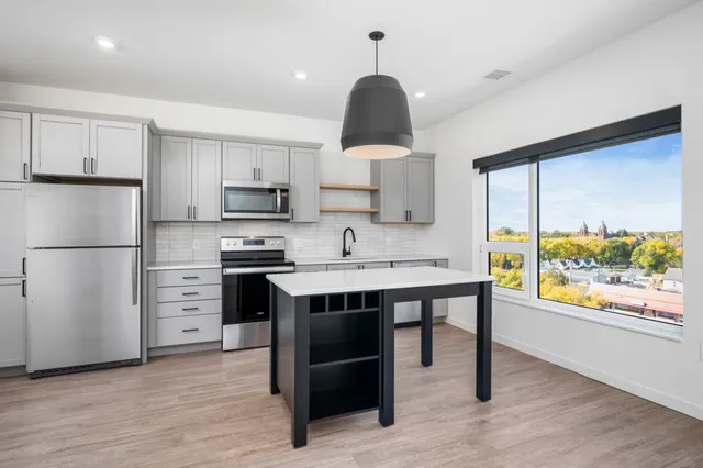 Modern kitchen with sleek gray cabinets, stainless steel appliances, and a spacious island, featuring large window with scenic views.