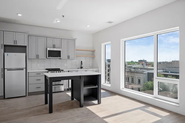 Modern kitchen with sleek cabinetry, central island, and large windows offering stunning city views.