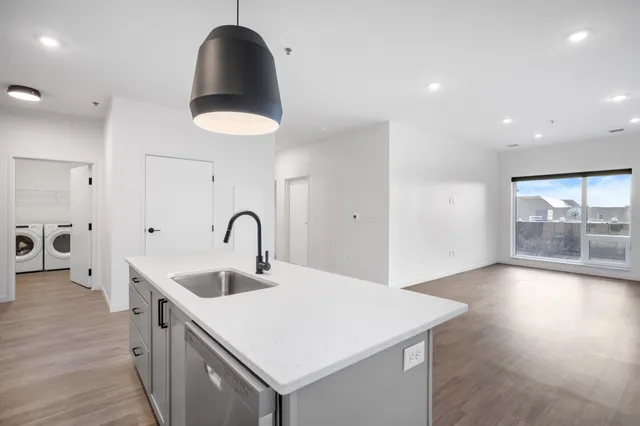 Bright, open-concept apartment with sleek kitchen island, modern pendant light, and in-unit laundry room.