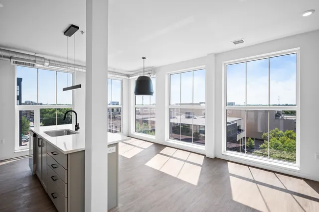 Bright, modern apartment with floor-to-ceiling windows, sleek kitchen island, and panoramic city views.