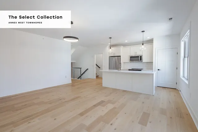 Contemporary open-concept kitchen and living area with sleek lighting and hardwood floors at Annex West Townhomes, part of The Select Collection.