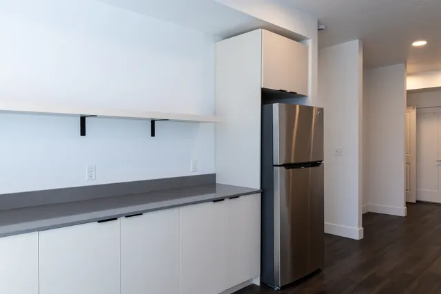 Modern kitchen with sleek cabinetry, stainless steel refrigerator, and open shelving, ideal for contemporary living.