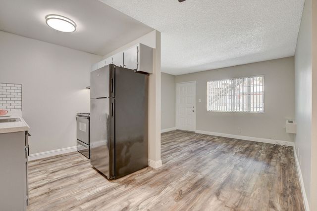 Modern kitchen and living area with open layout, featuring sleek appliances and wood flooring.