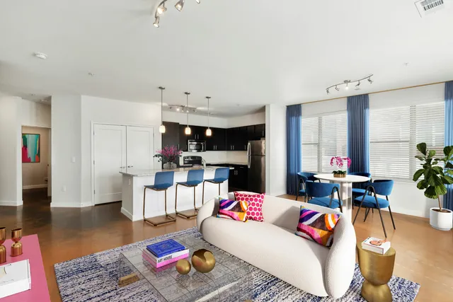 Modern open-concept living space with stylish kitchen, cozy dining area, and chic decor. Features vibrant accents and large windows for natural light.
