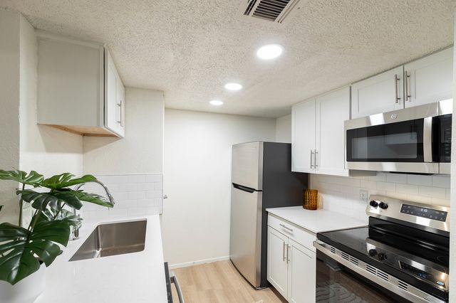 Bright, contemporary kitchen with stainless steel appliances, sleek white cabinetry, and modern lighting.