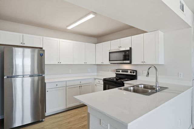 Sleek modern kitchen with stainless steel appliances, white cabinetry, and elegant quartz countertops.