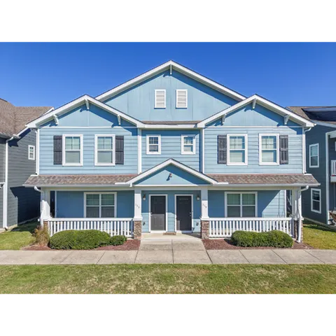 Charming blue duplex with modern design, featuring two front porches and beautifully landscaped surroundings.