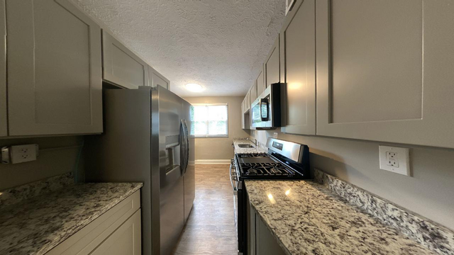 Modern kitchen with sleek granite countertops, stainless steel appliances, and ample cabinet space under natural light.