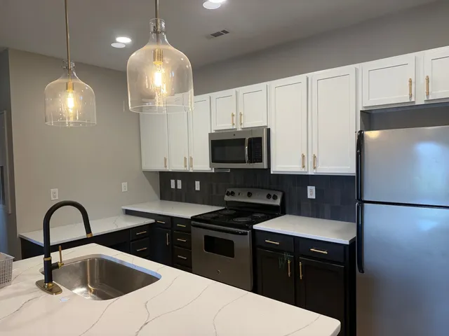 Modern kitchen with sleek white cabinetry, elegant pendant lighting, and stainless steel appliances.