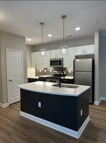 Modern kitchen with sleek cabinetry, stainless steel appliances, and elegant pendant lighting over a spacious island.