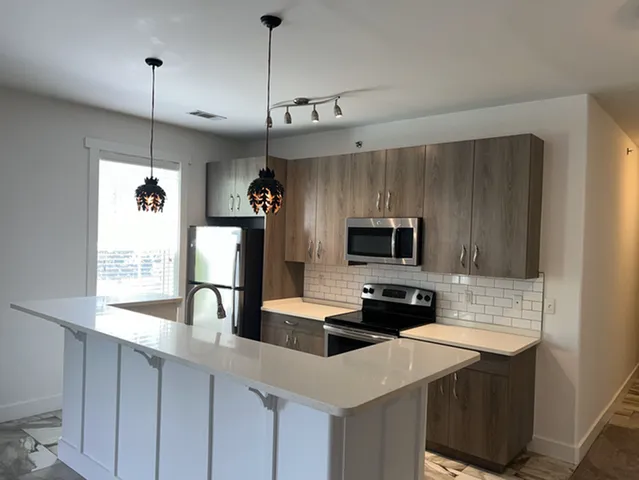 Modern kitchen design featuring sleek countertops, stylish cabinetry, and stainless steel appliances with elegant pendant lighting.