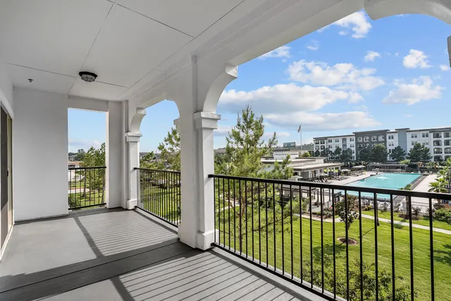 Charming balcony view showcasing a lush green landscape and a stylish pool area, perfect for relaxation.