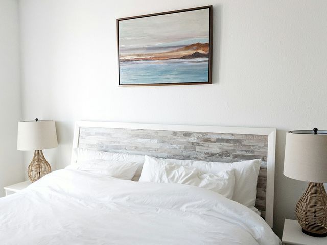 Cozy bed with matching nighstands and painting of coast on wall