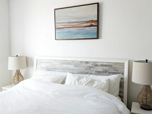 Cozy bed with matching nighstands and painting of coast on wall