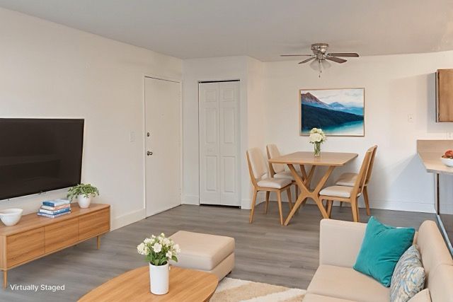 Charming living and dining area in a virtually staged apartment, featuring modern d&eacute;cor, a cozy sitting space, and elegant wooden furniture for a welcoming atmosphere.