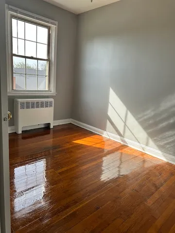 Bright, inviting room with polished hardwood floors and ample natural light from a large window.