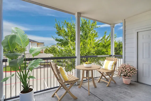 Charming balcony with wooden furniture, lush greenery, and scenic views, perfect for relaxing.