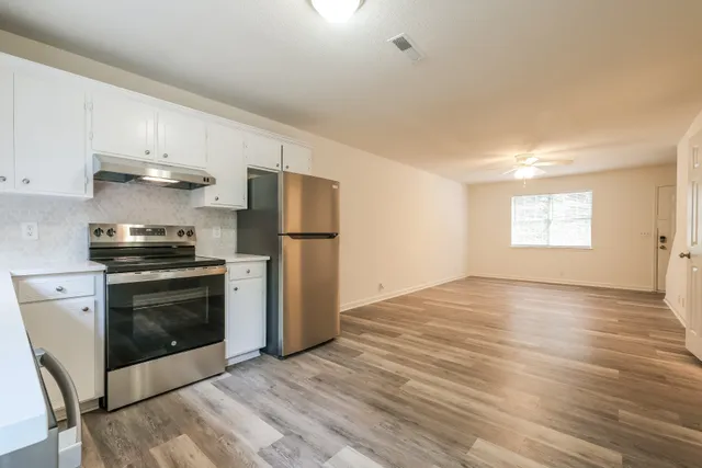Charming open kitchen and living room with sleek stainless steel appliances, modern cabinetry, and elegant wood flooring.
