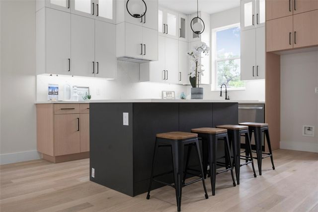Modern kitchen with sleek white cabinets, black island, and stylish bar stools, featuring ample natural light and elegant design.