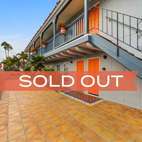 Charming apartment complex with vibrant orange doors and inviting tiled walkway, now sold out.