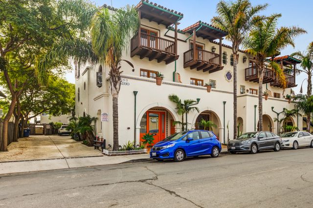 Charming Mediterranean-style apartment complex with lush palm trees and elegant balconies, offering a serene and inviting atmosphere.