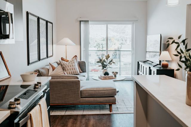 Elegant living room with modern decor, cozy sectional sofa, large sliding glass door for natural light, and stylish kitchen bar.