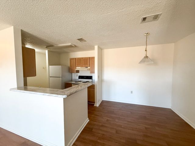 Bright and open apartment kitchen with modern cabinets and adjacent dining area with wooden flooring.