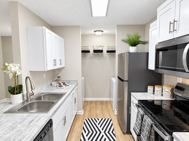 Modern kitchen with sleek stainless steel appliances, stylish white cabinetry, and elegant marble countertops. Features a cozy laundry nook and chic decor for a sophisticated touch.