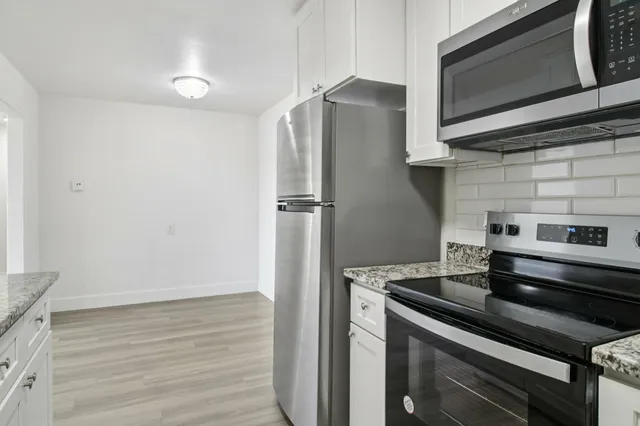 Modern kitchen with sleek stainless steel appliances, granite countertops, and bright white cabinetry.