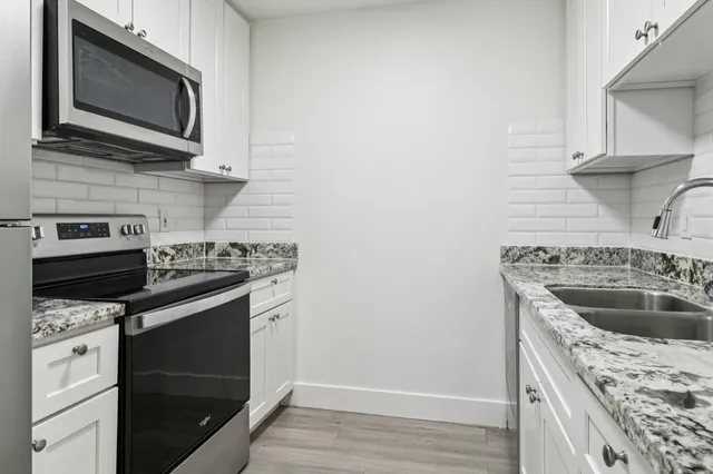 Modern kitchen with sleek granite countertops, stainless steel appliances, and elegant white cabinetry.