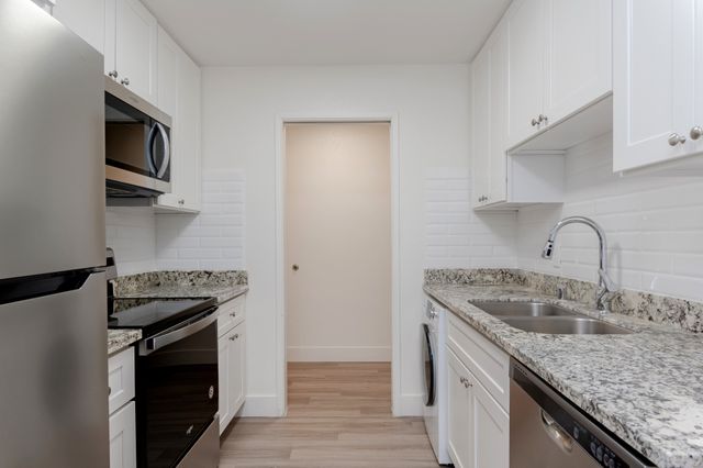 Modern kitchen with sleek stainless steel appliances, elegant granite countertops, and white cabinetry for a clean, sophisticated look.