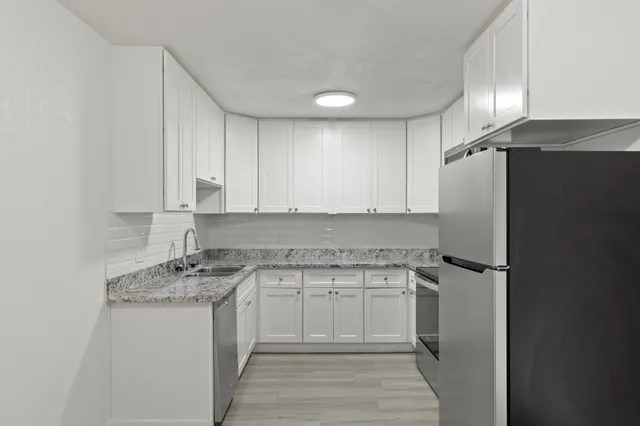 Modern kitchen with sleek white cabinetry, granite countertops, and stainless steel appliances.