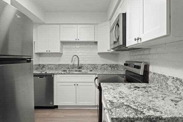 Modern kitchen with sleek stainless steel appliances, white cabinetry, and granite countertops, offering a stylish and functional cooking space.