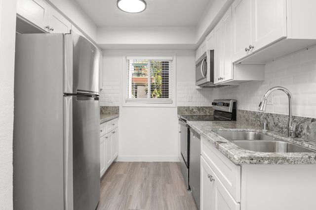 Modern kitchen with stainless steel appliances, white cabinetry, and granite countertops offering a sleek and bright cooking space.